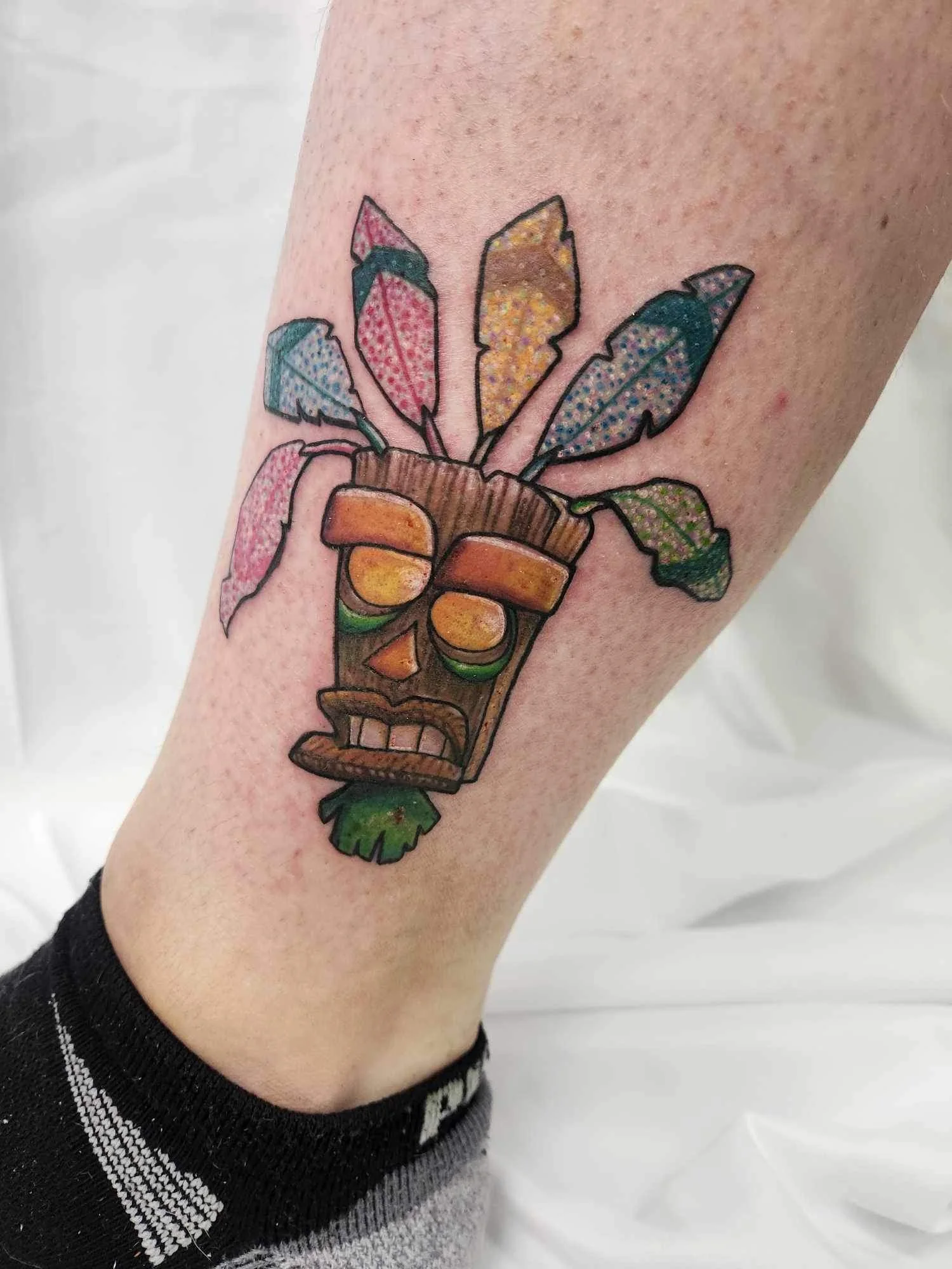 Tiki Mask Rainbow Feathers - new school tattoo by Saskatoon tattoo artist
